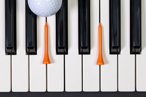 Virtuosic game - Piano keyboard and different golf balls and wooden tees