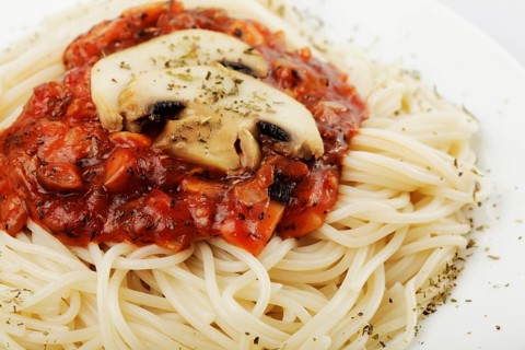 Spaghetti with tomato souce and champignons on white plate