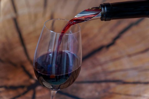 Red wine being poured into a glass on a wooden background