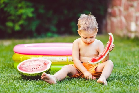 Theme summer seasonal food juicy watermelon berry. small funny Caucasian boy child two years