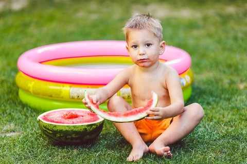 Theme summer seasonal food juicy watermelon berry. small funny Caucasian boy child two years