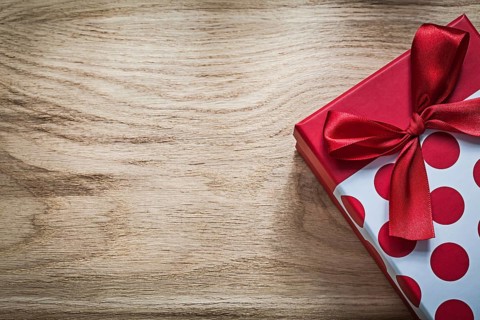 Gift box with red bow on wooden board holidays concept