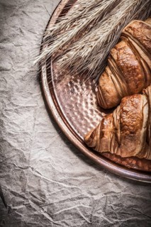 Golden wheat rye ears fresh croissants copper tray on wrapping paper