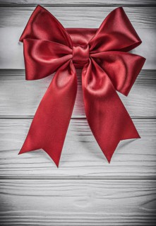 Paper roll with red bow on wooden board holidays concept