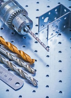 Perforated angle fasteners metal ruler drill and bits on metallic background construction concept