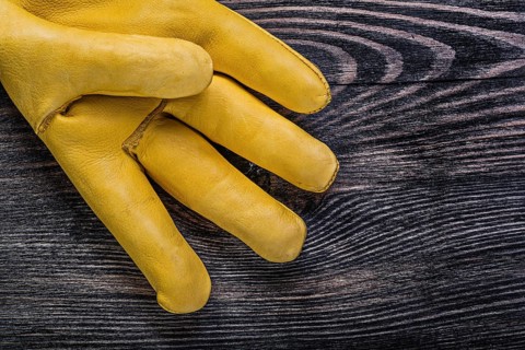 Leather yellow safety glove on vintage wooden board construction concept