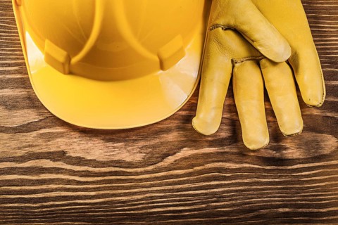 Leather safety gloves building helmet on wooden board construction concept