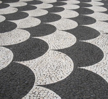 Traditional portugal black and white fish scale pattern tiled cobblestone sidewalk in funchal