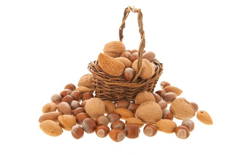 Assortment nuts in wicker basket isolated over white background