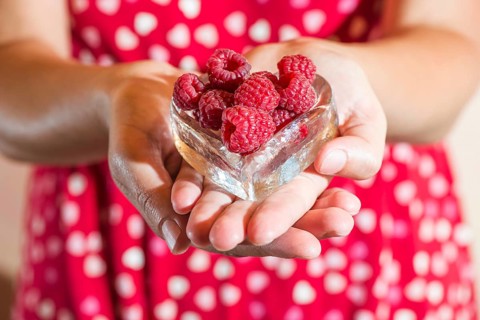 Woman in red dress holding a cup of raspberries