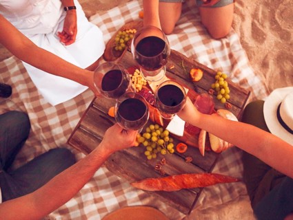 People drinking red wine outdoor. Summer picnic on the beach