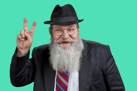 Portrait of happy bearded man showing victory sign. Isolated on green