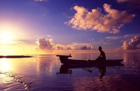 French Polynesia: Woman paddling in a small boat at sunset at Bora Bora Island and Lagoon Resort