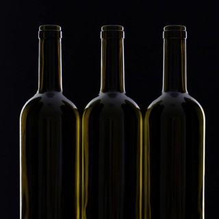 Three different bottles of wine on the black glass