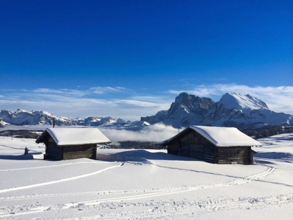Old wooden barns surrounded by deep snow with skiing tracks in the Dolomites, Italy