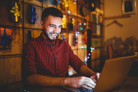 Theme training and computers. A young man with a beard and in a shirt uses a laptop, prints on the