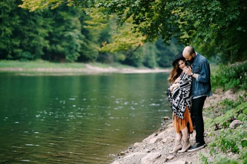 Man hugs a pregnant woman by the lake.
