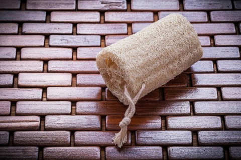 Loofah on textured wooden matting close up view healthcare concept