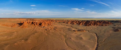 Aerial panorama view of the Bayanzag flaming cliffs at sunset in Mongolia, found in the Gobi Desert
