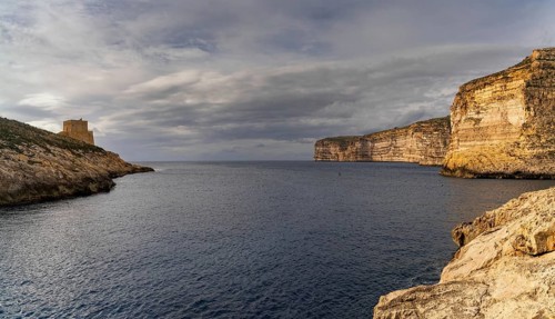 A view of the Xlendi Bay watchtower and cliffs on the coast of Gozo Island in Malta