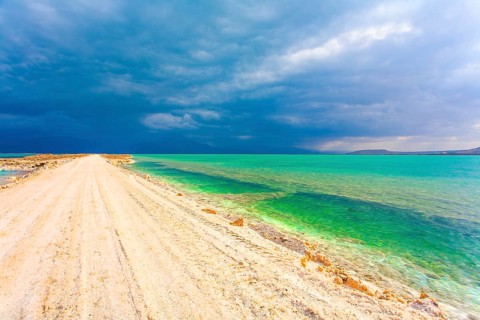 Low winter clouds are reflected in the green sea water. The landfill embankment runs through the