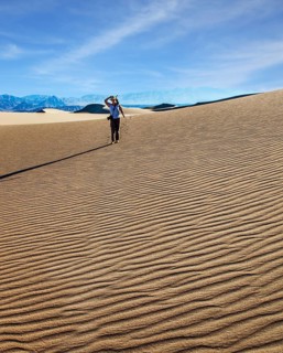 USA. Mesquite Flat Sand Dunes, Death Valley, California. Woman with a camera and a tripod goes