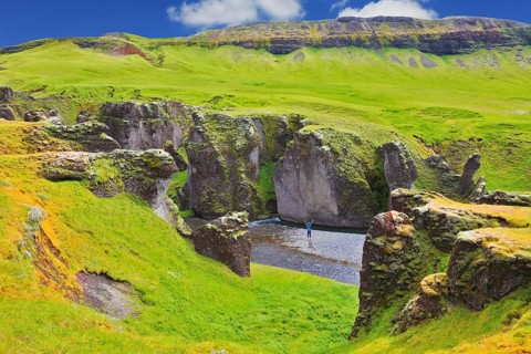 Enthusiastic woman - tourist on a rock canyon Fjadrargljufur. Fantastic country Iceland