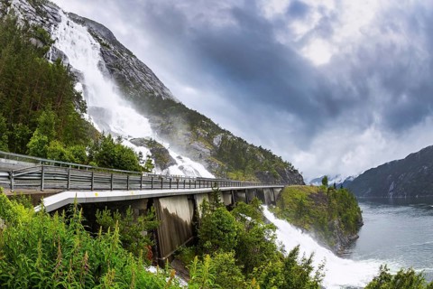 The cascading powerful Langfossen waterfall intersects with the highway and flows into the Acre