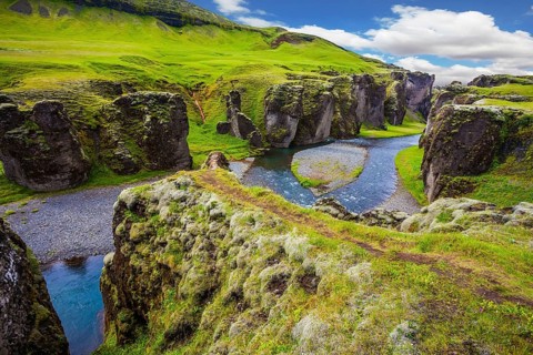 Magic canyon Fyadrarglyufur in Iceland. Green Tundra in July. Bizarre shape of cliffs and stream