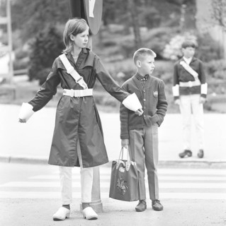 Junior safety patrol in the 1960s. A teenage girl stands with her arms out and signals to the
