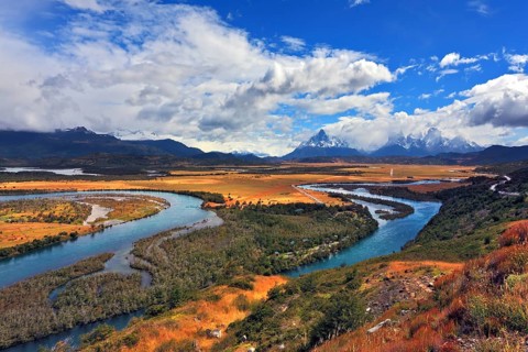 Glen Serrano. Meandering river bed of yellow autumn coast. Valley surrounded by snow-capped