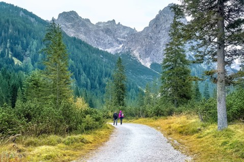 Hiking trip, Dolomites landscape. Pair of tourists is walking along a wide trail in the Dolomites.