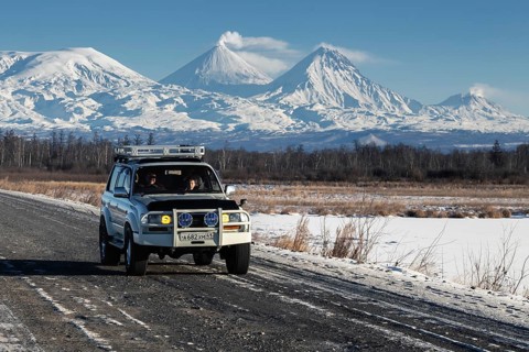 Japanese Sport Utility Vehicle Toyota Land Cruiser driving along road on background beautiful