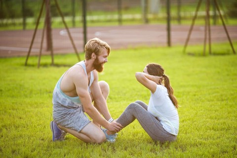 Sit ups fitness couple exercising sit up outside in graß Fit people working out cross training.