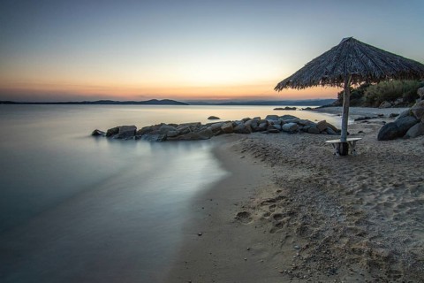 View through rocks on a sandy beach into the sunset. Landscape shot with view to the horizon over