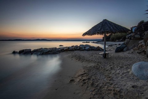 View through rocks on a sandy beach into the sunset. Landscape shot with view to the horizon over