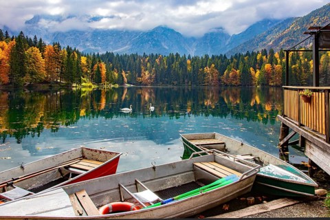 The boat dock. The Lago Fusine in Italy. The bright colors of the autumn forests are reflected in