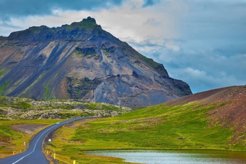 The road passes through the picturesque landscape in the mountains and lakes. Cloud Iceland in the
