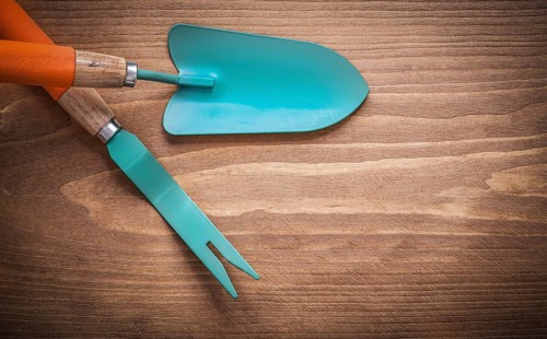 Metal root weeder hand trowel on wood board agriculture concept