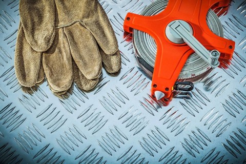 Leather safety gloves measuring tape on fluted metal sheet