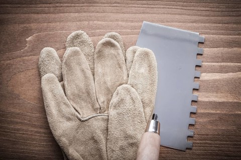 Working glove and putty knife on wood board