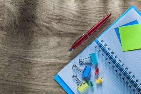 Reminder notes notebook pen drawing pins paper clips on wooden board