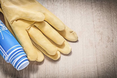 Protective gloves blue blueprints on wooden board construction concept