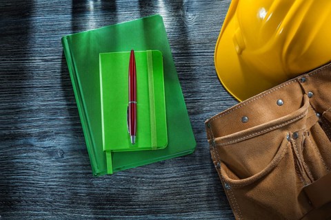 Notepads pen hard hat tool belt on wooden board