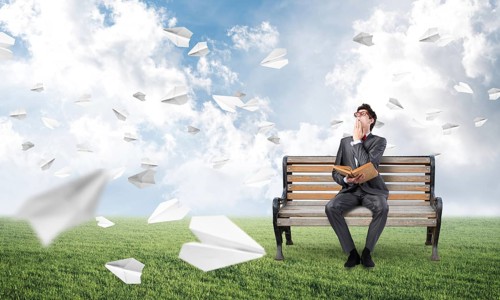 Young student with a book on the bench. traditional learning concept. paper planes fly around