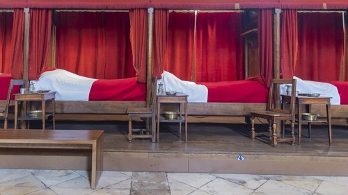 Beaune, France - April 29, 2024: Interior of main room with red beds at Hospices de Beaune or