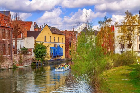 Ghent, Belgium, April 12, 2016: Old houses along canal and boat with tourists in popular touristic