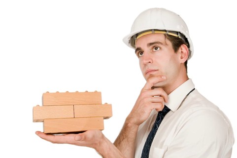 Upper body shot of a young man in a white shirt and white helmet with a stacked wooden block on his