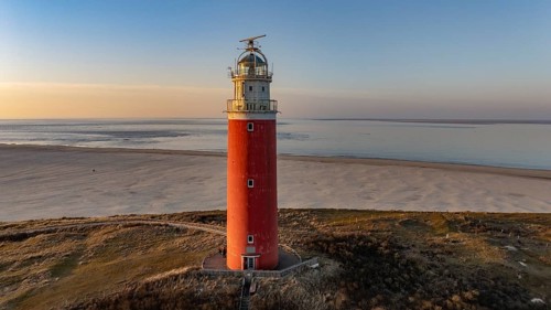 Aerial view of the northern end of the island of Texel with beach and lighthouse in sunshine, De