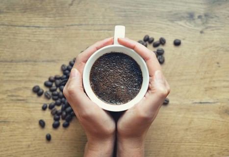 Woman holding cup of freshly brewed coffee